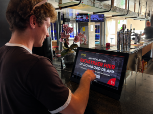 Self-service kiosk at a family entertainment center: guests checking in and buying sessions on a touchscreen